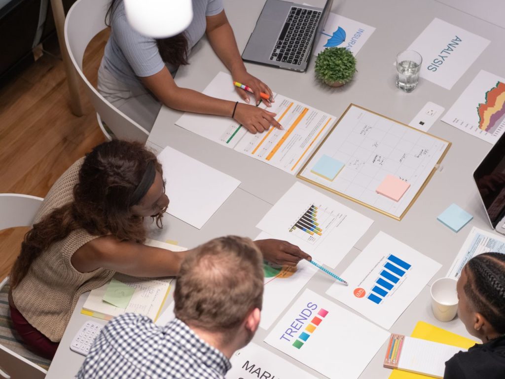 Team of professionals collaborating on a business project, analyzing charts and graphs in an office setting.